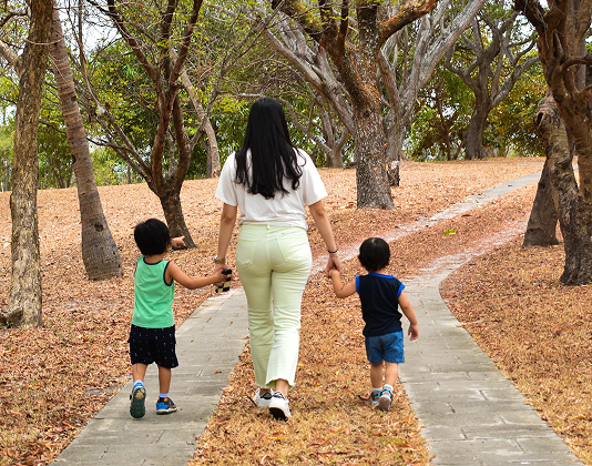Adulta caminando con dos niños por un sendero